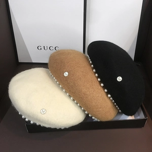 Detail of wool beret hats with white pearl trim and metallic M logo in various colors