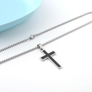 Minimalist black oil-drip cross pendant necklace in stainless steel on white background