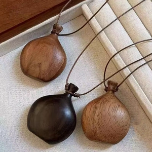 Three bohemian handmade wooden pouch pendant necklaces on a beige linen jewelry tray