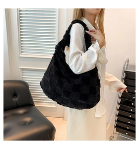 Detail of stylish black plush checkerboard tote bag worn by a model in casual setting