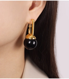 Vue macro de boucles d'oreilles en U plaquées or avec un pendentif en perle noire polie