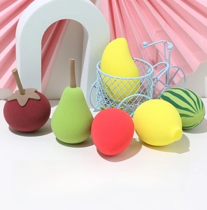 Detail shot of fruit-shaped makeup sponges featuring realistic strawberry and mango textures