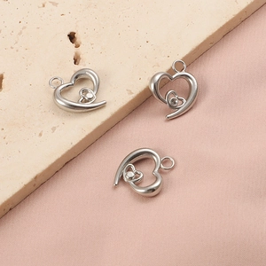 Three silver stainless steel hollow heart pendants with crystals on a textured background