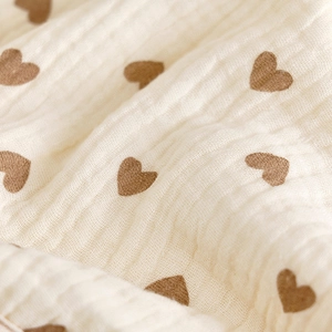 Detail of soft 6-layer cotton muslin bib with brown heart pattern and breathable texture