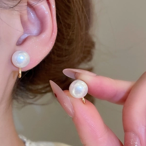 Macro detail of elegant white pearl ear clips with golden metal finish for non-pierced ears