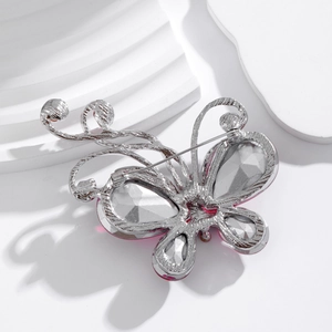 Elegant silver butterfly brooch with pink faceted crystals on a minimalist pedestal