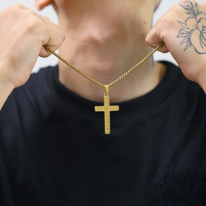 Close-up of a gold stainless steel cross pendant necklace worn by a man in black t-shirt