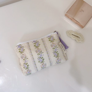 Detailed view of floral canvas storage bag with purple zipper and woven pull tab