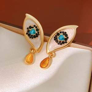 Detail of vintage eye-shaped earrings with blue heart gem and amber teardrop pendant