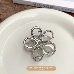 Detail view of a silver floral hair claw clip on a white plate with 4x4cm dimensions