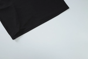 Detailed close-up of smooth stitching and fine fabric texture on the black dress hemline