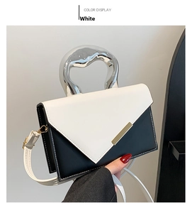 Detail of color-block crossbody bag with V-shaped flap and metallic top handle