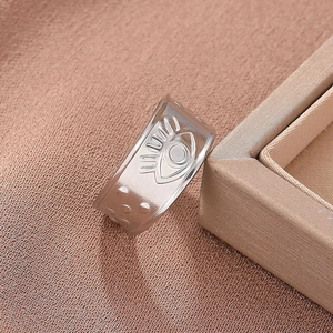 Macro shot of silver wide-band ring with embossed evil eye motif and dot relief details