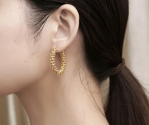 Detail of golden textured hoop earrings shown on a model for a vintage fashion style