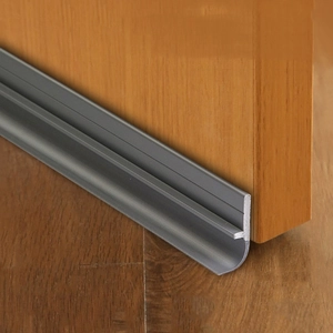 Close-up of grey silicone door bottom seal strip installed on wood for soundproofing