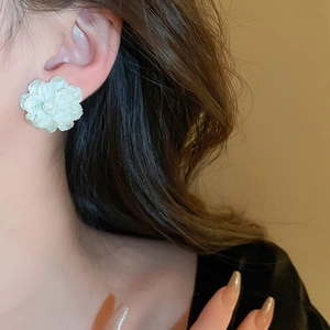 Close-up of elegant 3D white floral earring featuring multi-layered pearlescent petals