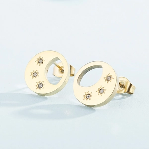 Détail de boucles d'oreilles dorées en acier avec croissants de lune et étoiles sertis
