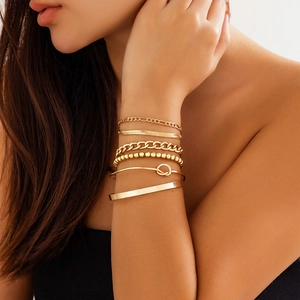 Close-up of a 6-piece gold-tone bracelet set including chains and beads on a model's wrist