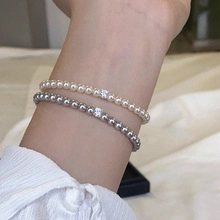Wrist shot of elegant pearl beaded bracelets featuring square zircon charms in two colors