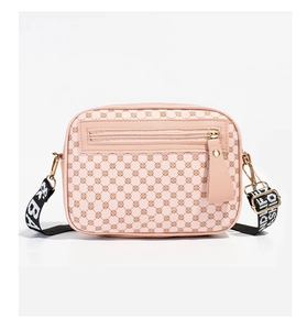 Detail of pink quilted crossbody bag with BAG lettered adjustable strap on white background