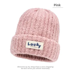 Close-up of pink chunky knit beanie with 'Lucky' logo patch on a white background