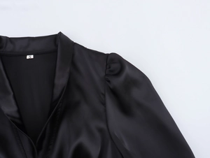 Detail of the V-neckline and puffed shoulders on a black satin mini dress, size S