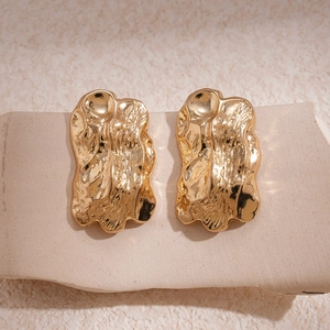 Minimalist golden irregular pleated earrings on a natural stone base
