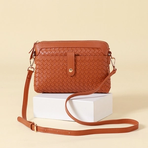Hand-woven crossbody bag in brown textured finish with adjustable shoulder strap and metal hardware