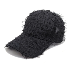 Detail of distressed black baseball cap showing frayed fabric and street style texture