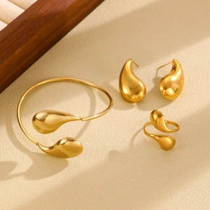 Detailed macro view of minimalist gold teardrop bracelet and ring jewelry set on a display