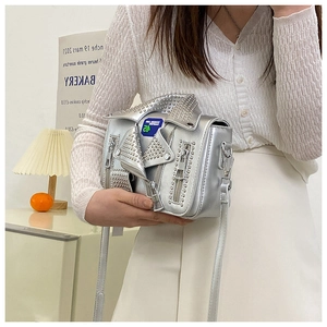 Detail of silver metallic biker jacket bag with rivets and zippers in a lifestyle setting