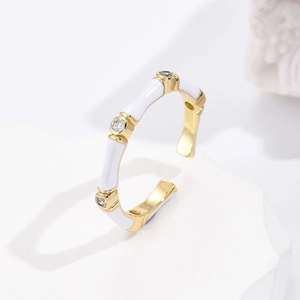 Detailed close-up of gold-plated bamboo-style open ring with white enamel and zircons