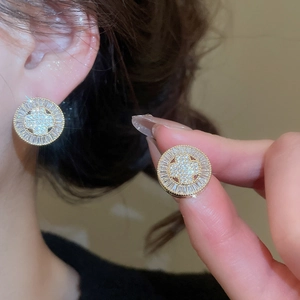 Detailed close-up of a gold-plated circular stud earring featuring zircon sunburst design