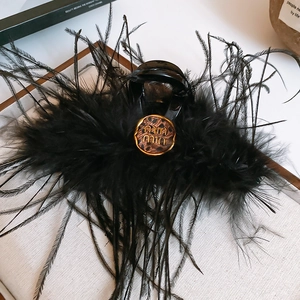 Gros plan d'une pince à cheveux en plumes noires avec logo léopard sur tissu