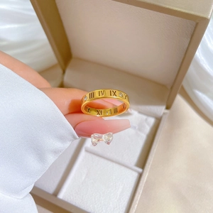 Macro detail of gold roman numeral ring with zircon stones held against a jewelry box