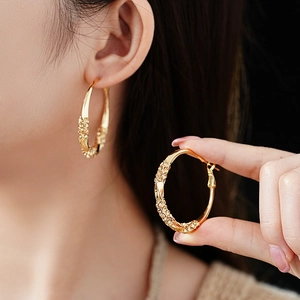 Detailed view of large gold twisted hoop earrings paved with sparkling crystals