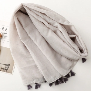 Detail of light grey cotton linen scarf with silver glitter and purple tassels