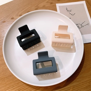 Three matte square hair claws in Morandi colors displayed on a white plate