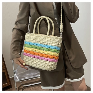 Detail of colorful rainbow striped straw handbag held by model in brown blazer