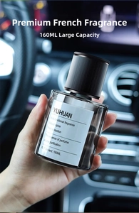 Close-up of 160ml dark glass car fragrance bottle held against blurred dashboard background