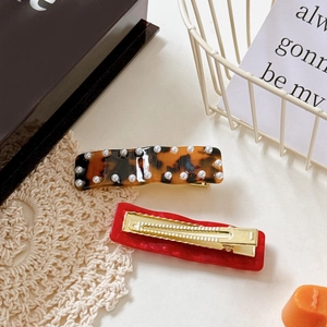 Acetate wavy hair clips with pearl accents in tortoiseshell and red finishes