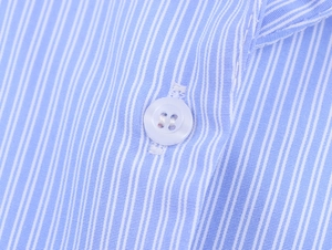 Macro detail of blue and white striped fabric texture with a white four-hole button