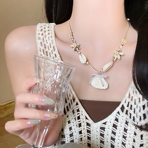 Detail of seashell necklace with starfish accents and pearl bow on gold chain