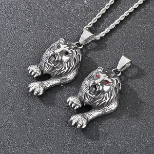 Detailed macro of lion head pendants in steel featuring red gemstone eyes and rope chain