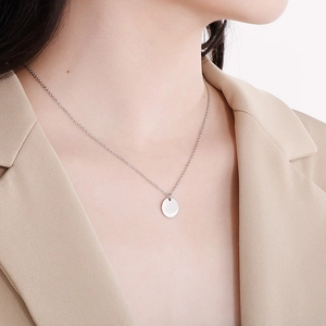 Gros plan d'un collier en acier inoxydable argenté avec pendentif rond minimaliste