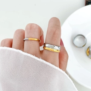 Close-up of stacked two-tone stainless steel rings worn on finger with minimalist design