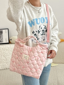Sac bandoulière matelassé rose avec motif lapin et fleurs porté par une femme