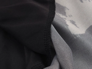 Detailed close-up of brushstroke print mesh fabric and black smooth textile stitching