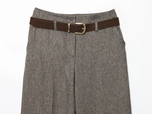 Detail of herringbone trousers waist with dark brown belt and gold buckle