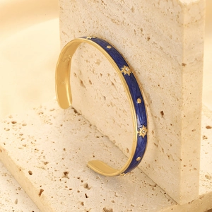 Detailed shot of gold plated stainless steel bangle with blue enamel and star patterns